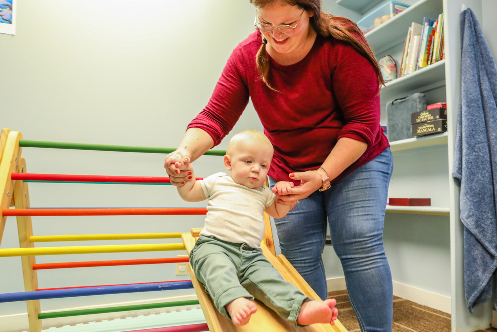 woman helping baby on toy slide