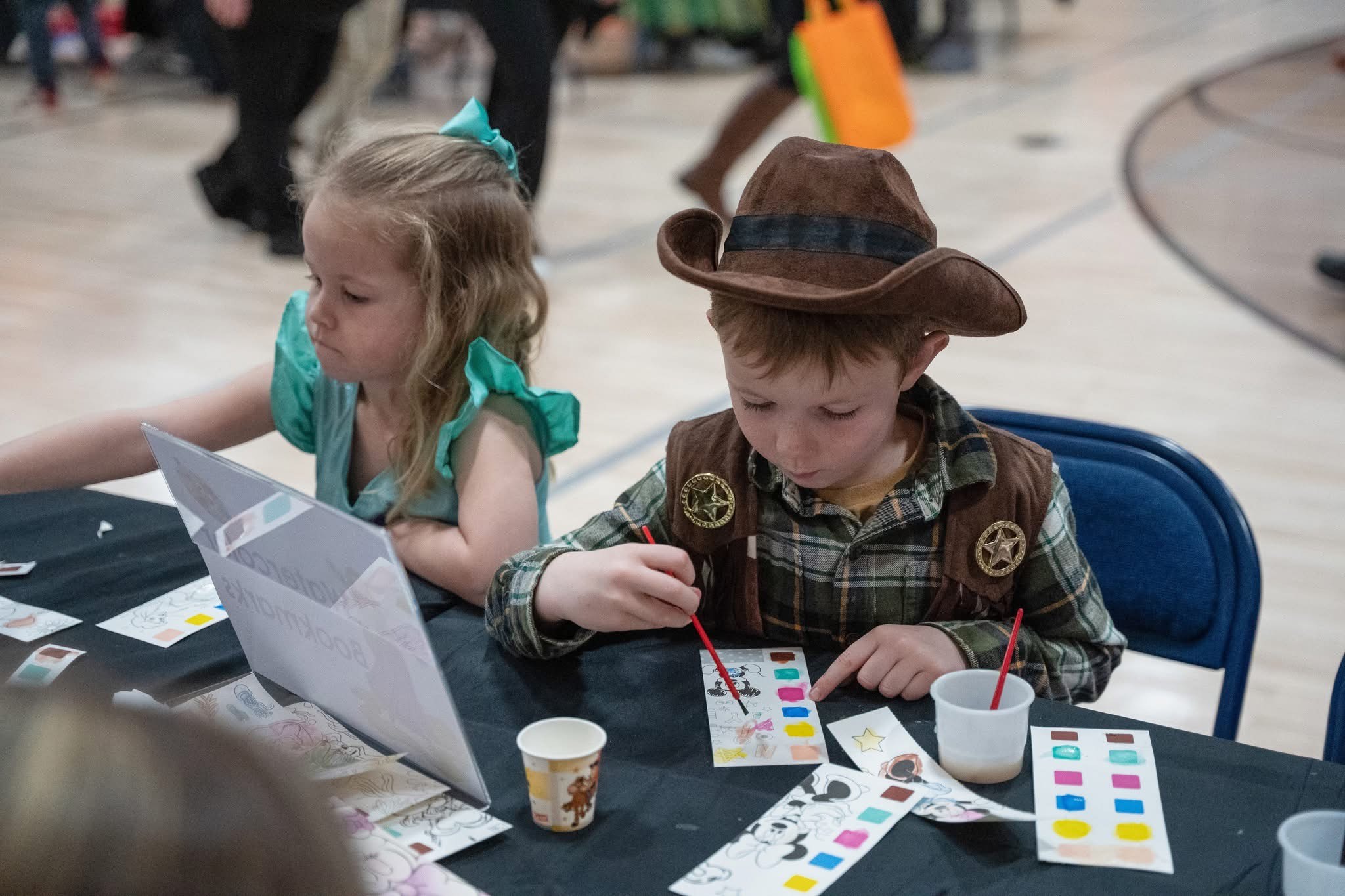 Girl in princess costume and boy in cowboy costume doing crafts
