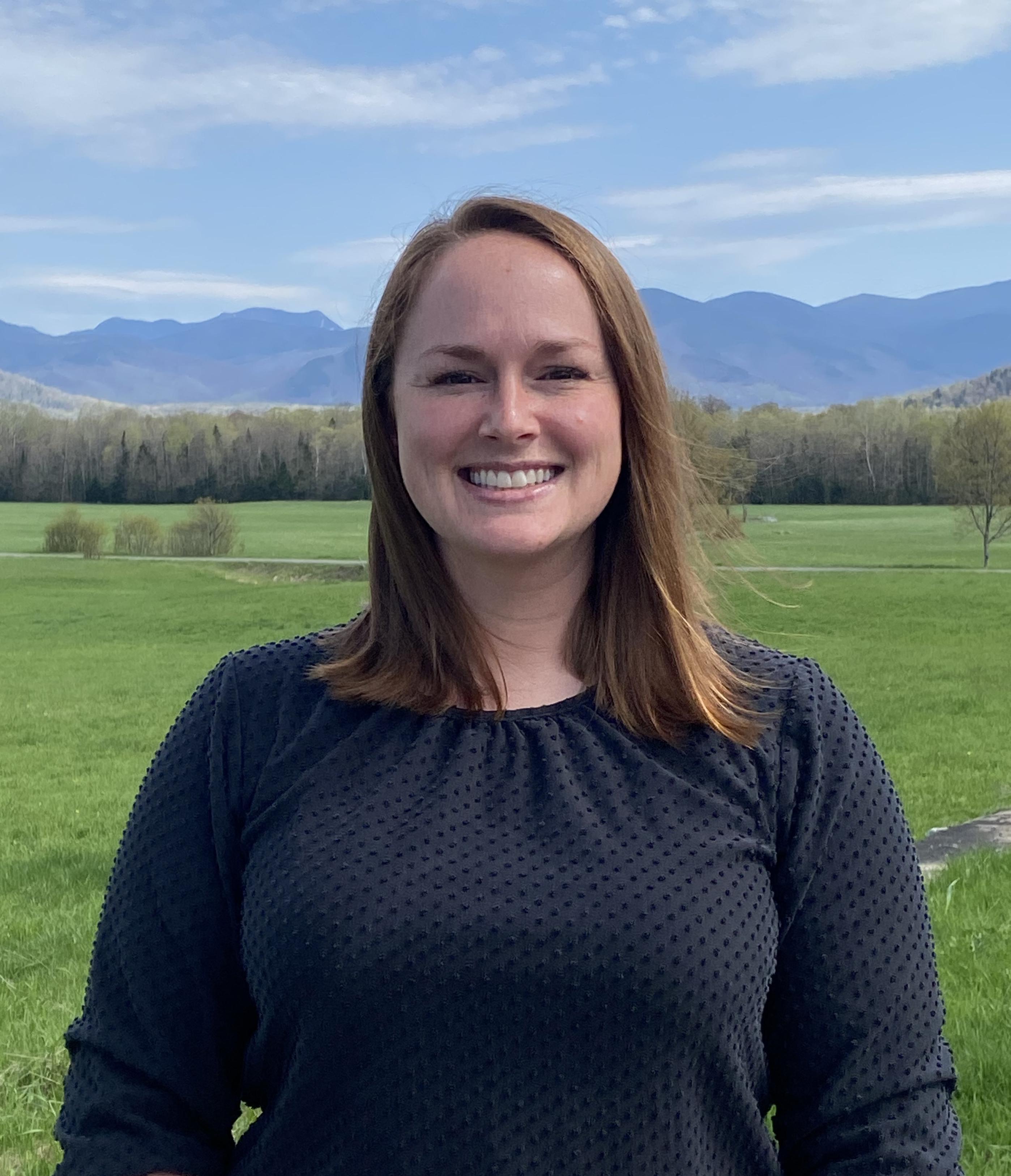 Kim standing in front of a field and mountain range.
