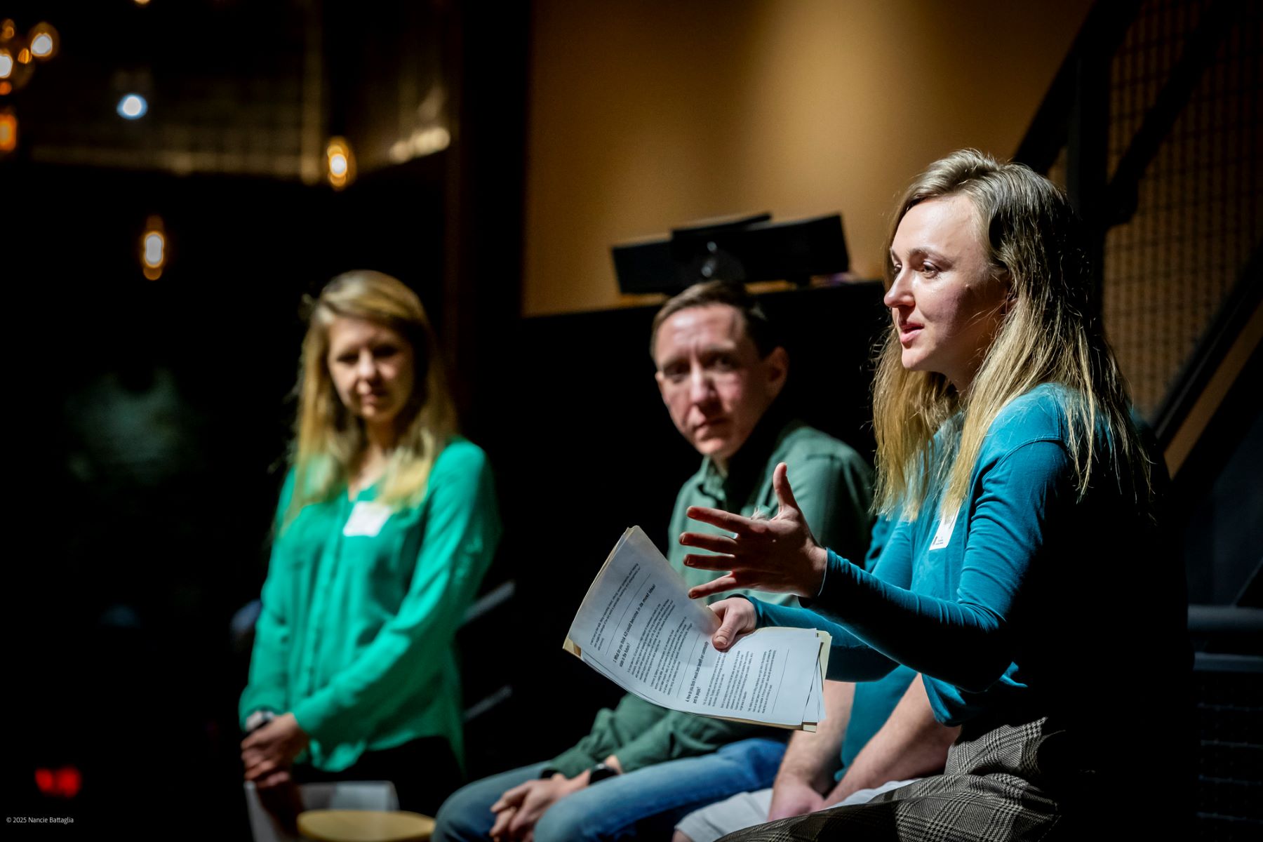 a woman is speaking while a man and another woman look on