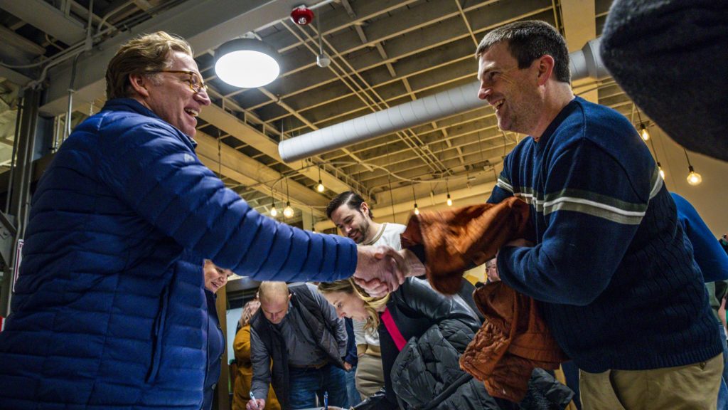 Two men shaking hands at indoor event