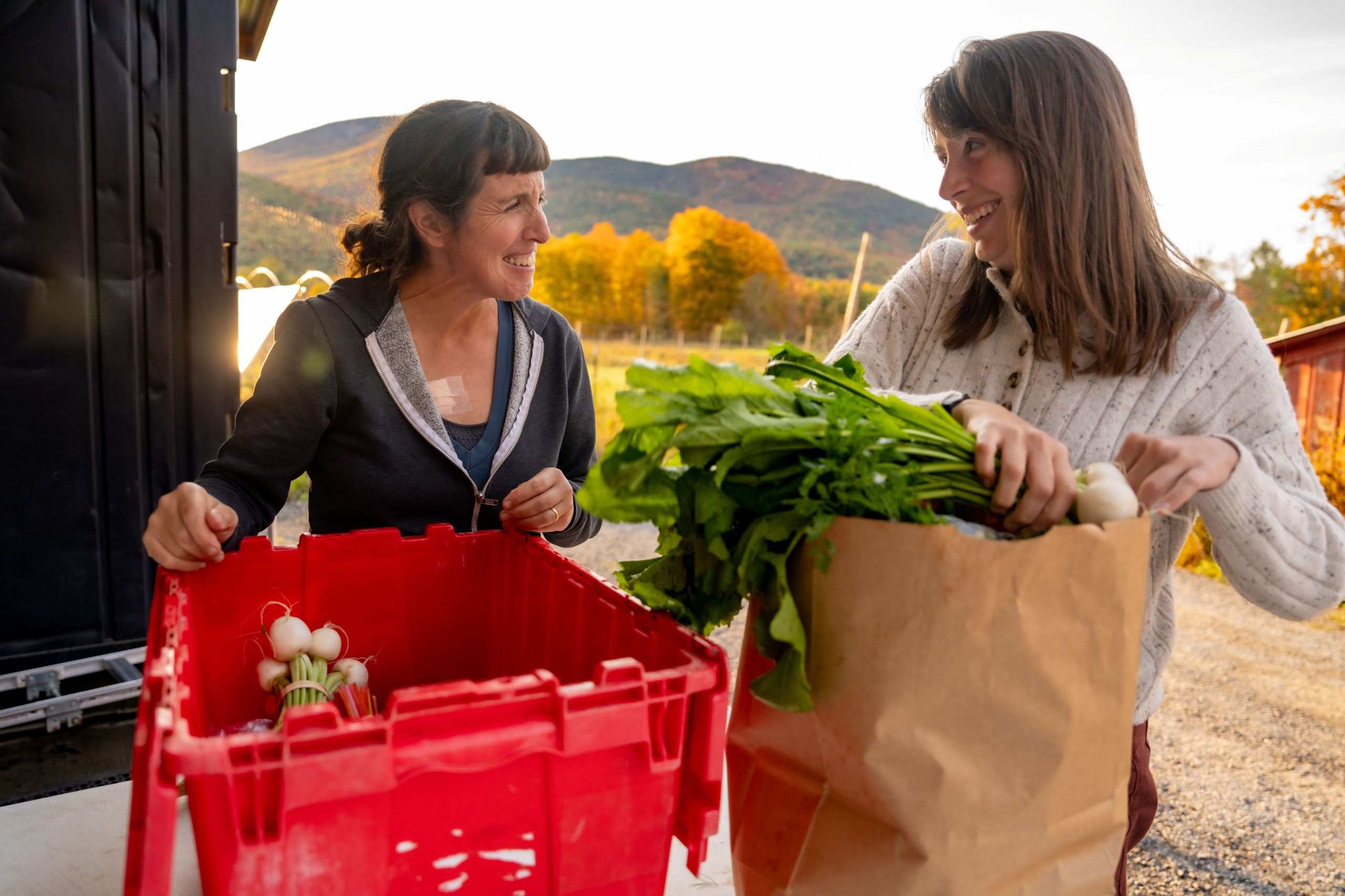 Two woman standing behind local produce outside
