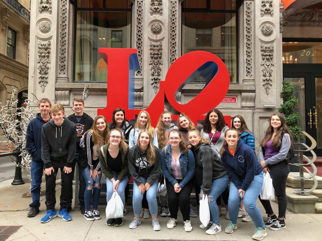 Group of students pose below love sign